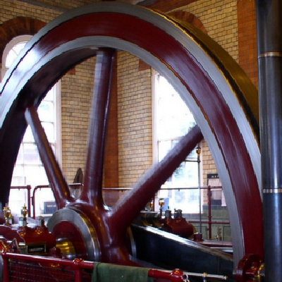 Enormous red industrial age flywheel as part of antique machine